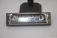 Close-up photo of Bluesband harmonica showing engraved metal cover plate with brand name 'BLUESBAND International'.