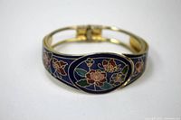 Top angled view of the cloisonné flowered bracelet showing floral enamel design against dark blue background.
