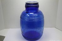 Front view of large cobalt blue glass jar with embossed lettering on surface