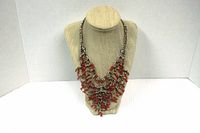 Full front view of the gold tone coral branch style necklace on display stand, showing two strands with coral-like enamel branch design and multi chains on top half.