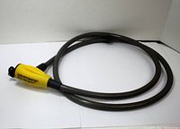 Full view of the coiled Kryptonite Flex Security bike lock showing black braided steel cable and yellow lock mechanism.