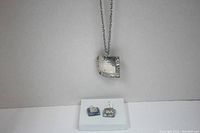 Full view of the necklace with pendant, earrings, and gift box on white background.