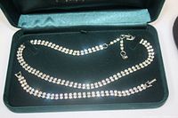 Photo showing the two-row rhinestone necklace and matching bracelet neatly placed inside a green velvet-lined box.