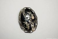 Oval Siam sterling silver brooch with black enamel base and gold-tone dragon designs, twisted rope border, excellent condition.