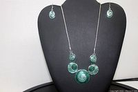 Front view of necklace and earrings displayed on black stand showing overall appearance and length.