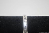 Close-up view of the sterling silver bangle bracelet's animal cut-out designs and polished surface.