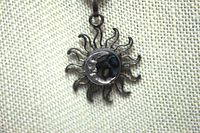 Close-up image of the sterling silver pendant showing sun design with abalone shell center and man in the moon face detail, highlighting patina.