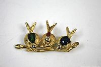 Front-facing view of the gold tone brooch showing three birds on a branch with green, red, and dark blue enamel accents.