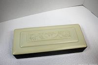 Overhead view of rectangular cream colored trinket or jewelry box with detailed decorative panel showing bird and flowers on the lid.