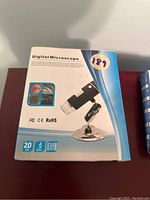 Front view of the digital microscope box showing image of the microscope and product features like 20 megapixels camera, 5 LEDs, 500x magnification, and 30 FPS video.