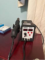 Front view of YIHUA 898D+ rework station showing digital displays, control knob, and buttons with hot air gun holder.