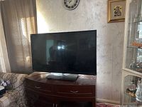 Front view of LG TV on wooden cabinet, showing screen and stand.