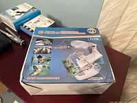 Close-up photo of sealed box for TH-7023 welding magnifier tool with LED lights, helping hands, and magnification.