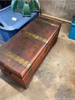 View of closed vintage cedar chest showing brass straps and wooden exterior with scratches