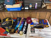 Wide view showing various sports collectibles including NASCAR posters, Rusty Wallace backpack, Phillies helmets, Barry Bonds plaque, and Whitey Ford signed baseball