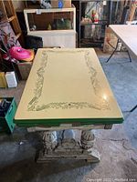 Full view of rectangular enameled kitchen table showing cream top with green decorative border, storage drawer under top, and carved wooden legs with distress finish.