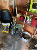 Overview of garden items including pots, plant stand, tools, metal bucket, soil bag, and lawn waste cart in shed