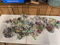 Overview of ziplock bags filled with assorted Smurf figurines on white folding table