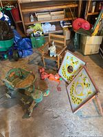 Set of vintage child's toys in a garage including metal stroller, folding chair, pull toys, plastic cat, clown boards