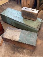 Photo of two vintage wooden tool chests, one long green painted with metal handle, one smaller with worn wood and faded paint