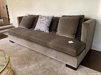 Front-left angled view of grey velvet sofa with cushions showing overall design and condition