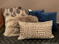 All six pillows arranged together showing variety of textures and patterns including velvet, fur, sequins, and geometric prints.