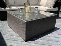 Front-left perspective of square wicker coffee table with glass top on deck