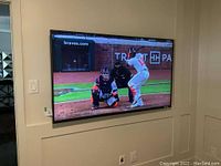 TV powered on displaying baseball game, wall-mounted