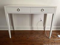 Full front view of desk showing two drawers, ring pulls and tapered legs