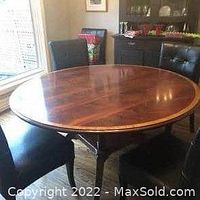 Assembled table in dining room showing round banded mahogany top and four splayed legs.