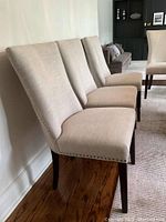 Four chairs aligned against a wall showing side profile and leg finish