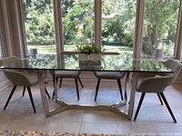 Overall view of glass top table and chrome base in room with chairs