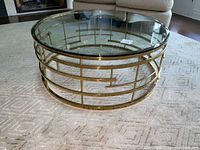 Front view showing clear round glass top and geometric gold-finished base
