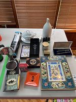 Overall view of all items on table including Persian art frame, pen set, diffuser, flask, decorative fork and spoon, crystal stopper, small dishes, and containers