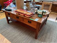 Full angle view of the oak coffee table showing top surface, drawers closed, and slatted side panels.