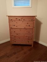 Front view of pine wood dresser showing six drawers and metal knobs.