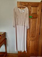 Full view of the Avanti Designs ladies evening dress hanging showing front beadwork and skirt length