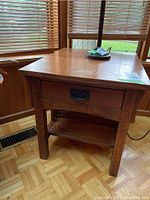 Front view of one oak side table showing drawer closed and slatted sides