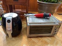 Ultrean air fryer on left, Breville toaster oven on right. Wooden floor and furniture background.