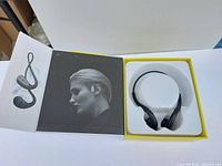 Black over-ear wireless sports earbuds displayed in an open box with packaging showing an image of a person wearing the earbuds.