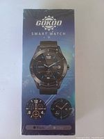 The photo shows a sealed retail box for a Gokoo smart watch. The front of the box highlights the watch design and some round digital watch face options in black and grey.