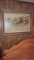 Framed western cowboy scene painting on wood panel wall showing overall view.