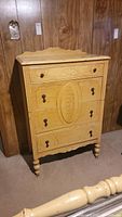 Front view of vintage four drawer chest showing decorative carved panels and metal pulls on a pale yellow painted finish.