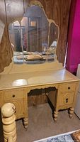Full view of the vintage vanity dresser showing the mirror, drawers, and legs, with visible wear.