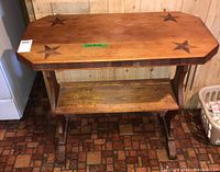 Front view of a wooden side table with star inlays on the top and a lower shelf.