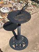 Full view of the outdoor metal sundial showing detailed engravings and rust spots.