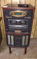 Front view of the wooden audio cabinet featuring gold dials, a digital display, dual cassette decks, and speaker grills.