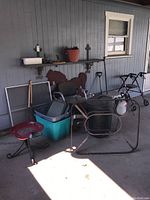 Photo showing metal walker, wooden stool, wooden horse silhouette, trash cans, and a metal chair frame.