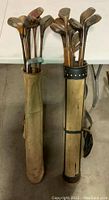 Two golf bags filled with antique golf clubs, showing overall lot size and condition
