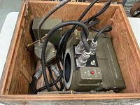 Open wooden crate showing camera housing, power module, junction box and cables